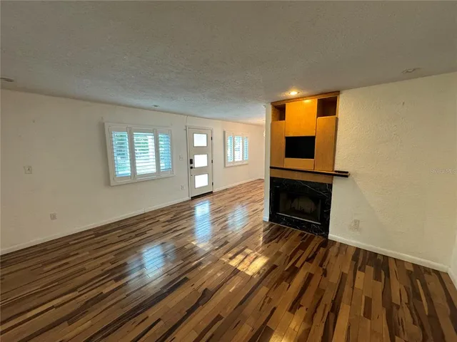 a view of empty room with wooden floor and fireplace