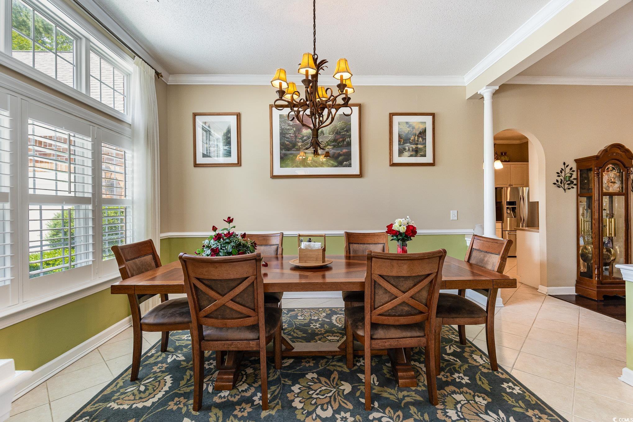 1004 Addington Court Murrells Inlet, SC 29576 - Photo 5 of 40 Dining room with light tile patterned flooring, arched walkways, ornamental molding, a chandelier, and decorative columns