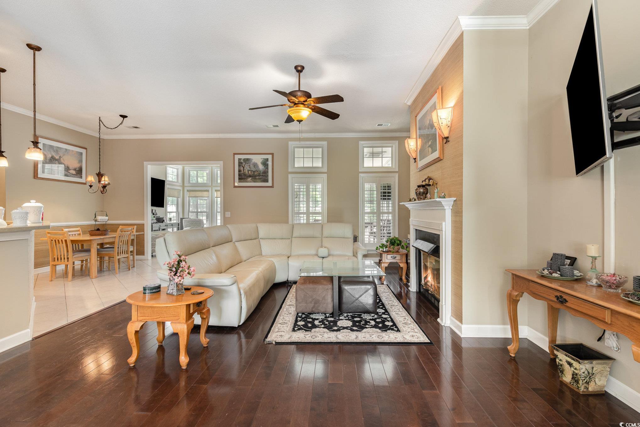 1004 Addington Court Murrells Inlet, SC 29576 - Photo 7 of 40 Living room with ceiling fan, a glass covered fireplace, wood finished floors, and ornamental molding