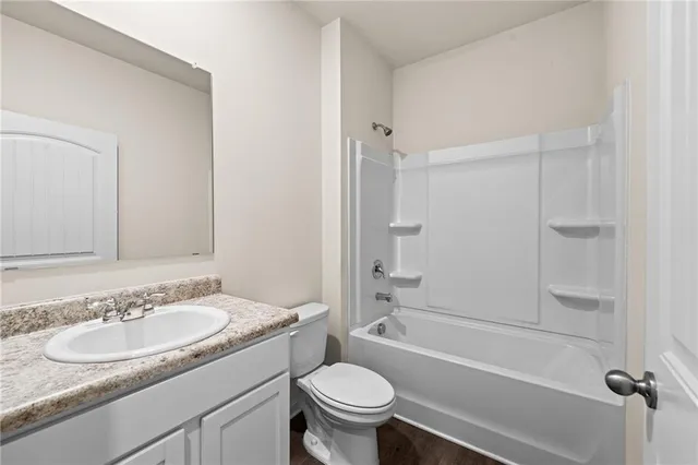 a bathroom with a granite countertop sink a toilet a mirror and shower