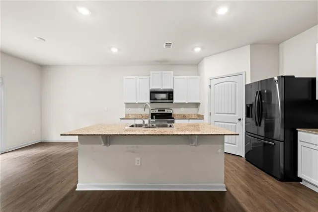 a kitchen with stainless steel appliances granite countertop a refrigerator a stove top oven a sink and dishwasher with wooden floor