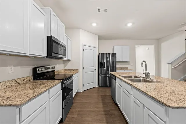a kitchen with stainless steel appliances granite countertop a sink stove microwave and refrigerator