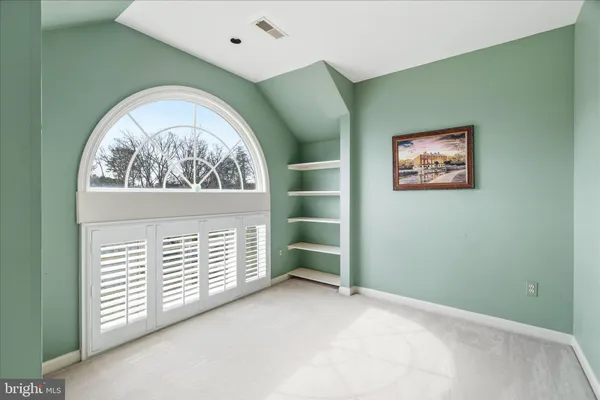 an empty room with a chandelier fan and windows