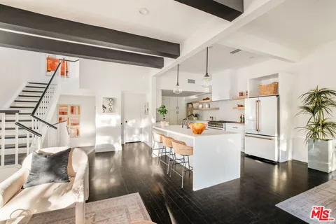 a kitchen with stainless steel appliances a refrigerator a stove a sink and white cabinets with wooden floor