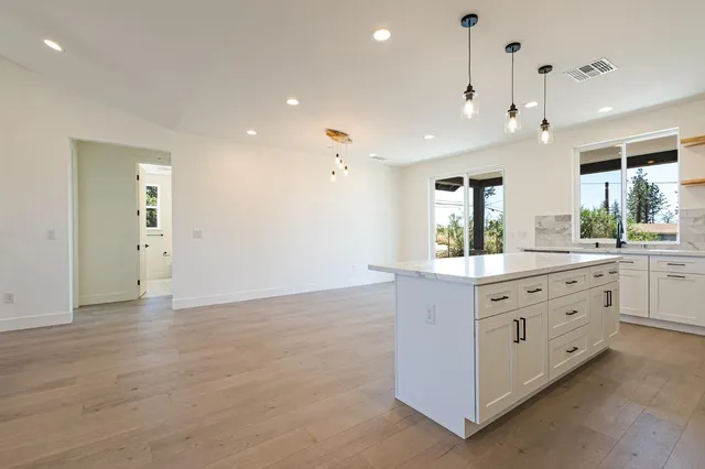 a large room with a lot of white cabinets and wooden floor