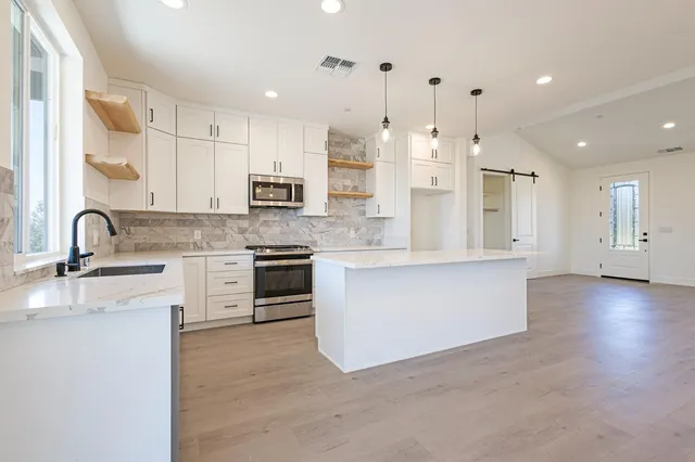 a large kitchen with stainless steel appliances kitchen island a white counter space a sink and cabinets