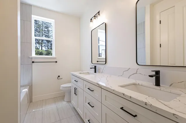 a bathroom with a double vanity sink mirror and toilet