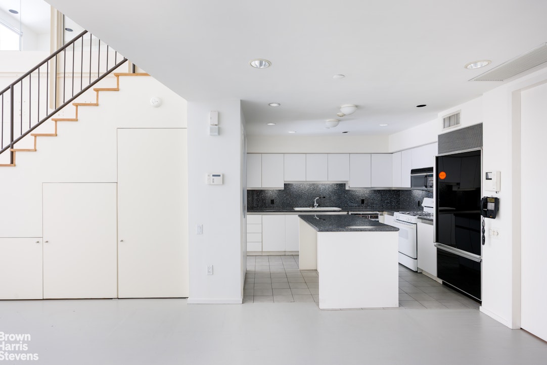 42 Downing Street Manhattan, NY 10014 - Photo 16 of 25 a kitchen with stainless steel appliances a refrigerator and a stove top oven