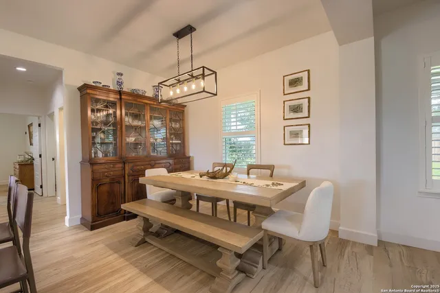 a dining room with wooden floor a chandelier a wooden table and chairs