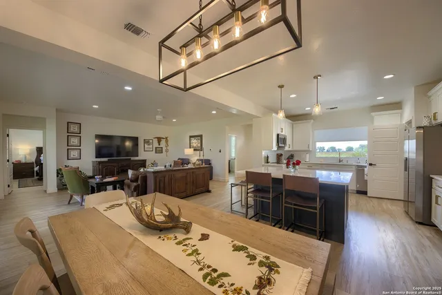 a kitchen with stainless steel appliances kitchen island granite countertop a table chairs and a refrigerator