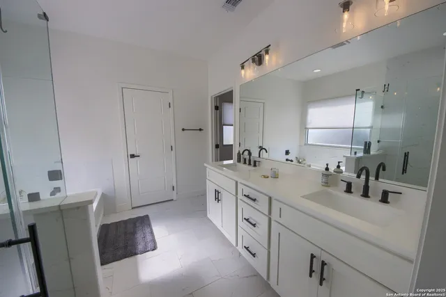 a bathroom with double vanity sink a mirror and a shower