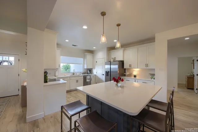 a kitchen with a dining table chairs stainless steel appliances and cabinets