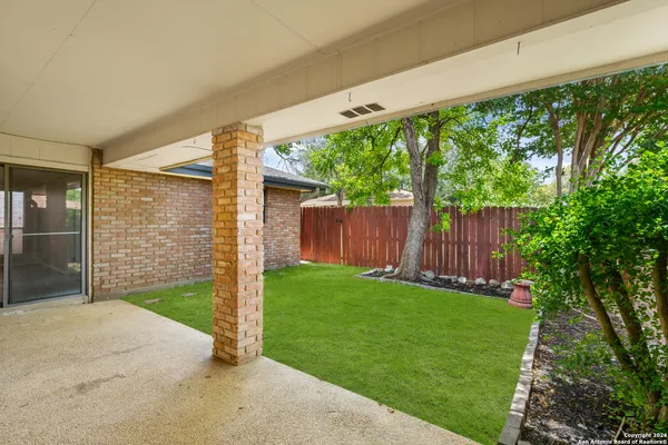 a view of a backyard with large trees and wooden fence