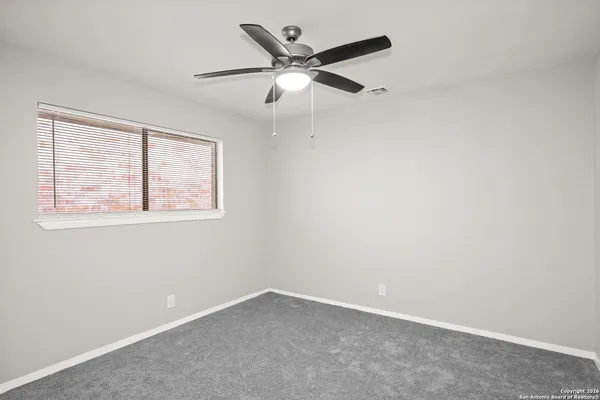 an empty room with a window and a ceiling fan