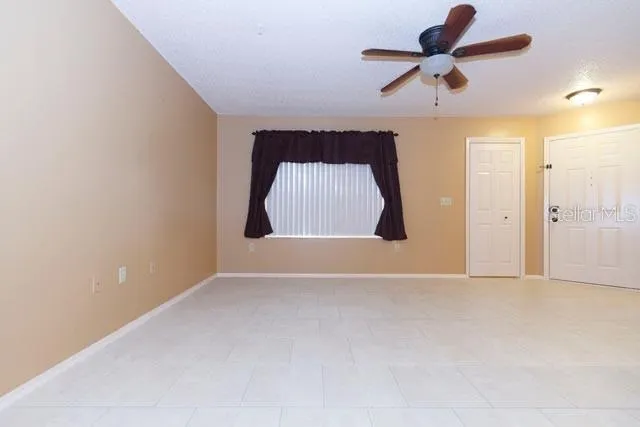 an empty room with ceiling fan and window