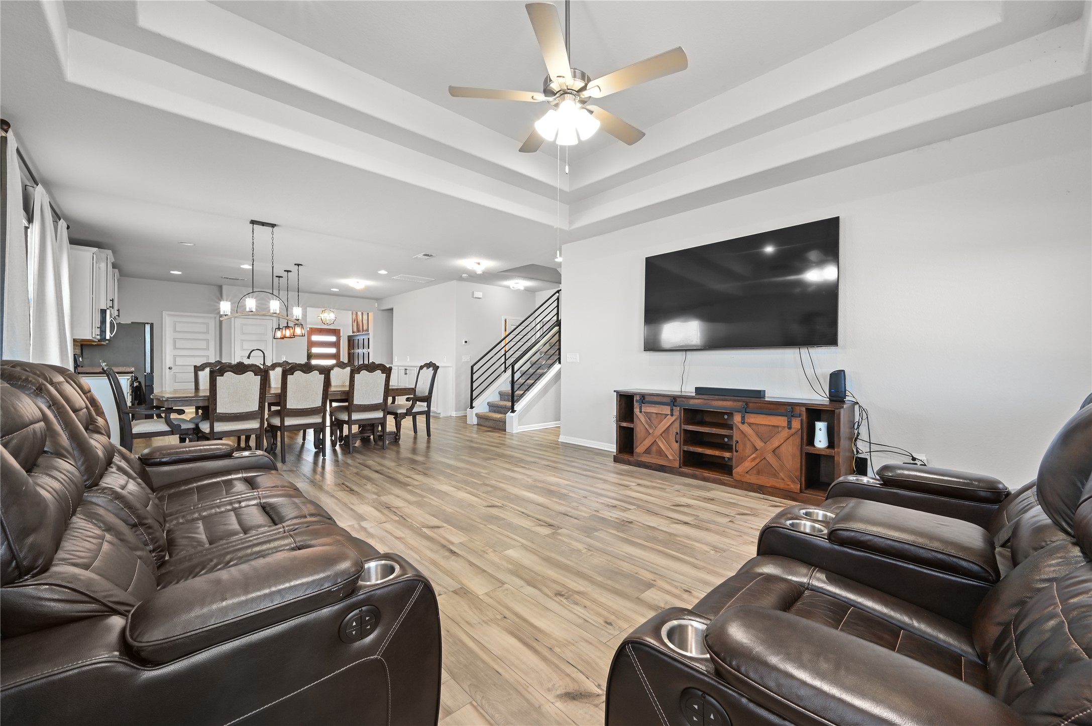207 Dogvane Circle Kyle, TX 78640 - Photo 13 of 32 Living room with light wood-style floors, a tray ceiling, suspended lighting, and a ceiling fan