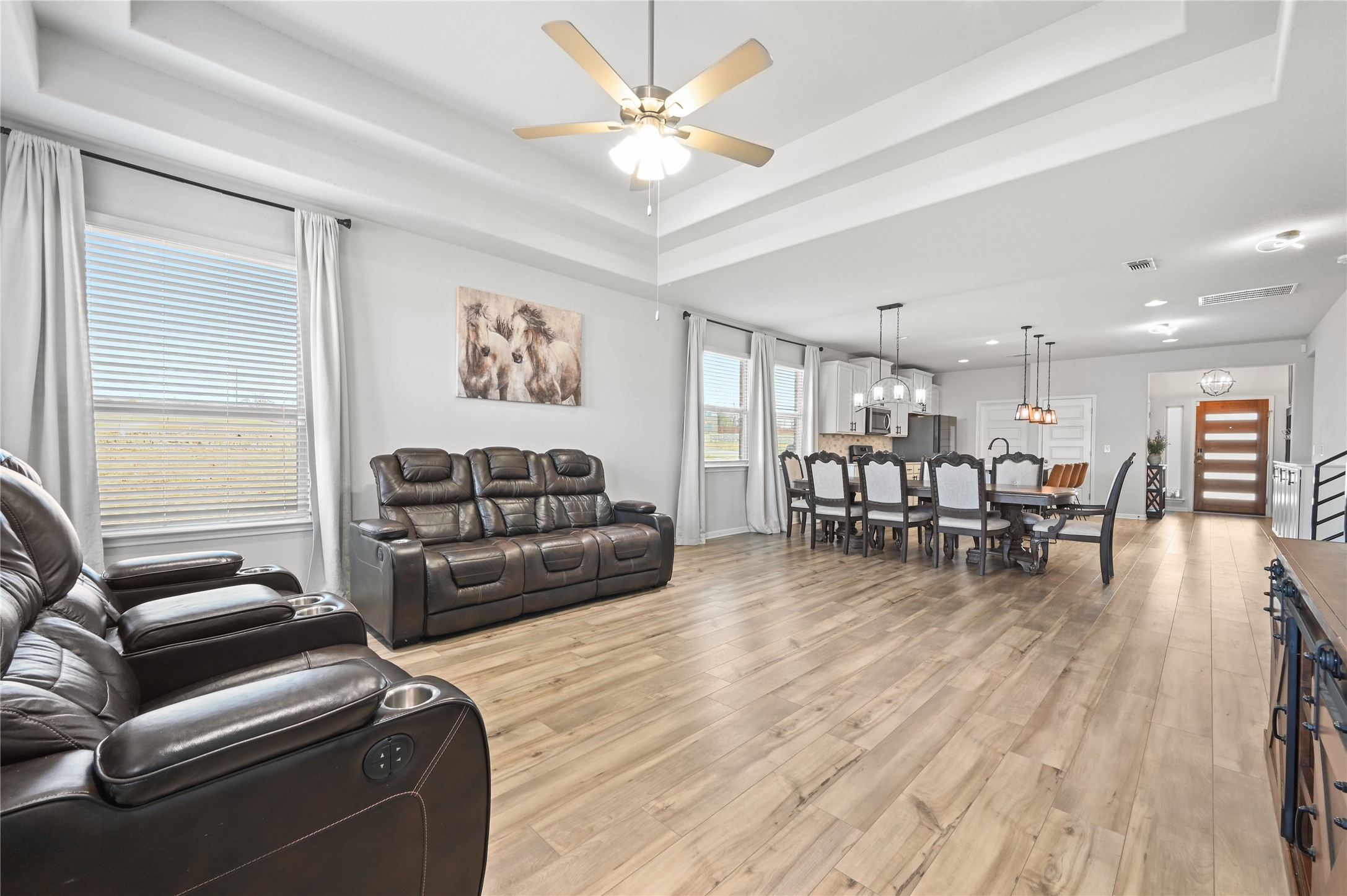 207 Dogvane Circle Kyle, TX 78640 - Photo 14 of 32 Living area featuring light wood-type flooring, a ceiling fan, and a tray ceiling