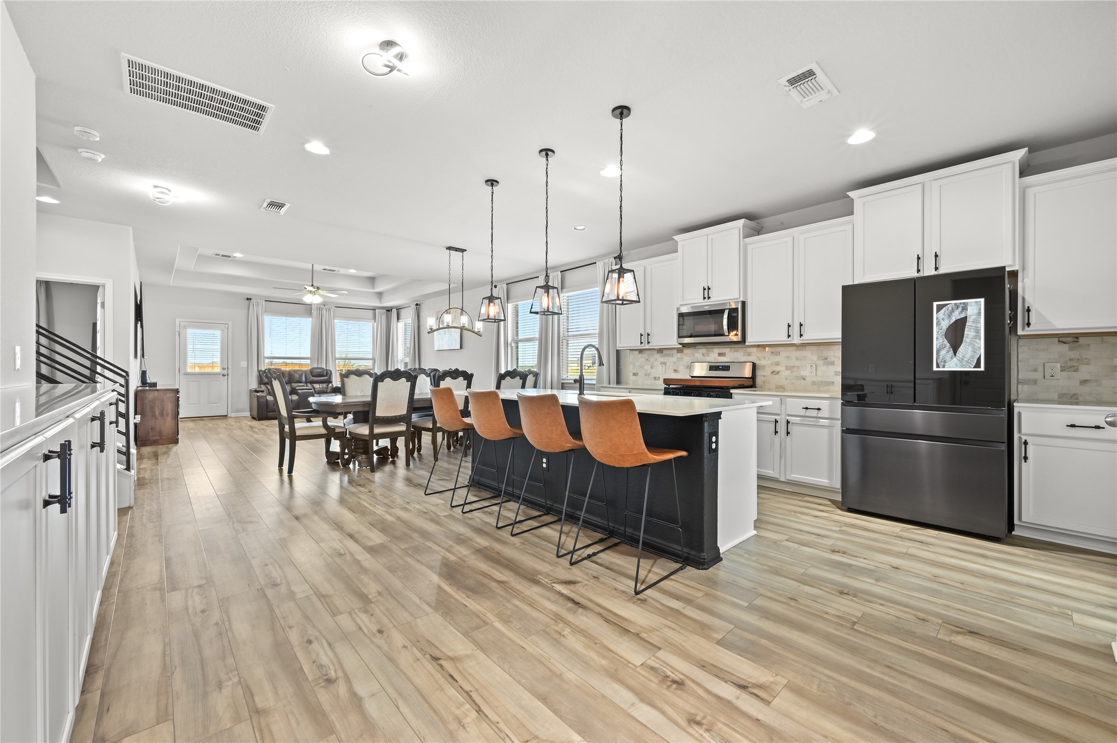 207 Dogvane Circle Kyle, TX 78640 - Photo 6 of 32 Kitchen featuring stainless steel appliances, white cabinets, hanging light fixtures, a center island with sink, and a breakfast bar
