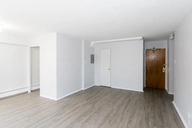 a view of an empty room with wooden floor and closet