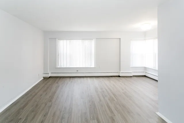 an empty room with wooden floor and window