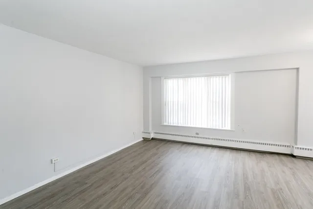 an empty room with wooden floor and window