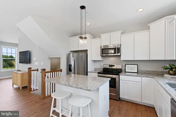 a kitchen with stainless steel appliances granite countertop a stove top oven a sink and white cabinets