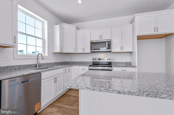 a kitchen with kitchen island granite countertop a sink window and cabinets