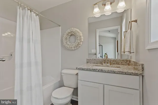 a bathroom with a granite countertop sink mirror vanity and toilet
