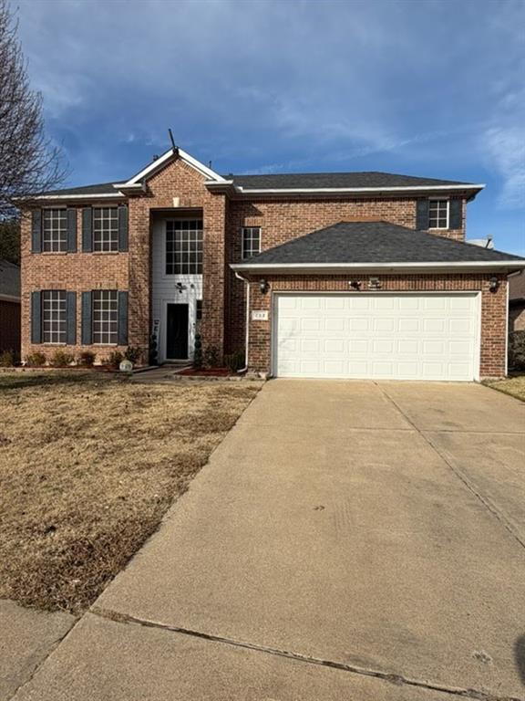 View of front of property with brick siding, an attached garage, and driveway
