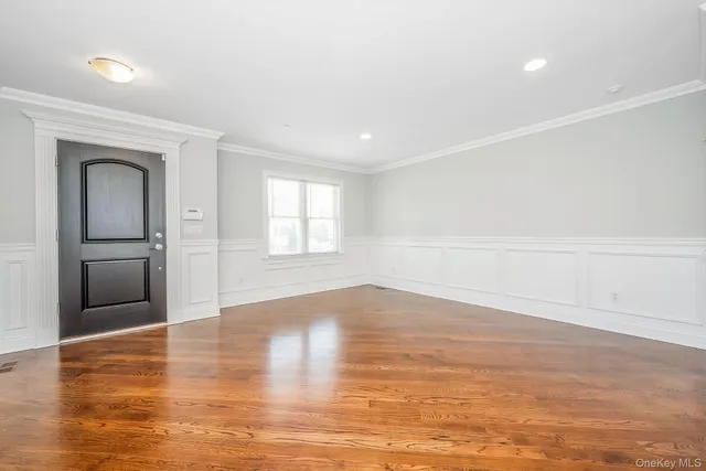 a view of empty room with wooden floor and kitchen