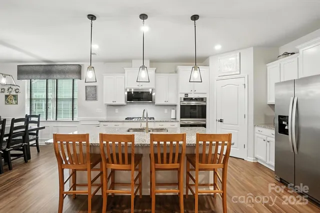 a kitchen with stainless steel appliances a dining table chairs and white cabinets