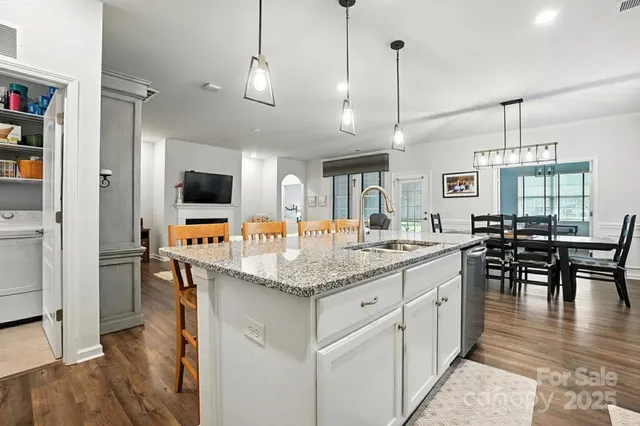 a kitchen with stainless steel appliances kitchen island granite countertop a stove a sink and a wooden floors