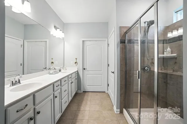 a spacious bathroom with a double vanity sink a large mirror and shower