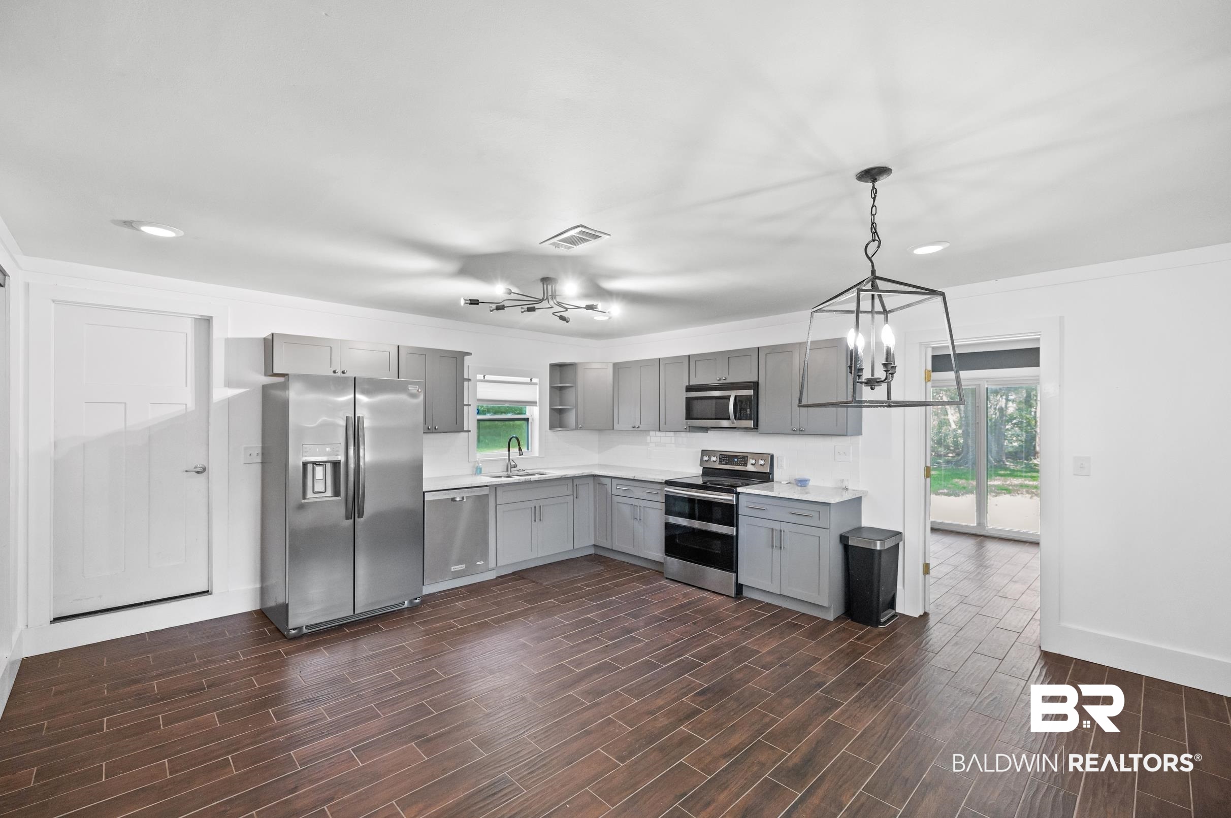 24663 Chestnut Street Elberta, AL 36530 - Photo 5 of 22 Spacious kitchen featuring wood-finish flooring, light grey cabinetry, stainless steel appliances, white countertops, and a subway tile backsplash