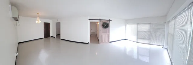 an empty room with windows and refrigerator