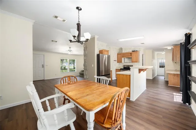 a view of a dining room and livingroom with furniture wooden floor a chandelier