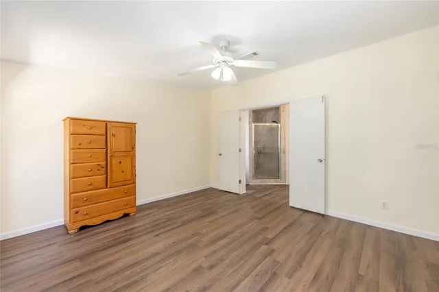 an empty room with wooden floor closet and windows