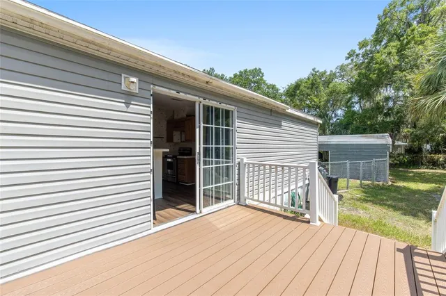 a view of backyard of house with wooden fence and large trees