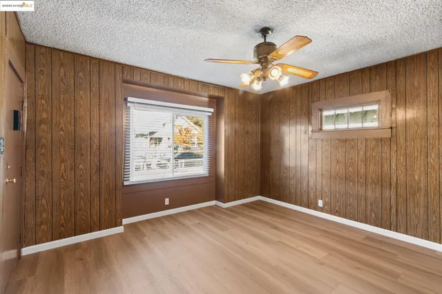 a view of an empty room with window and chandelier fan