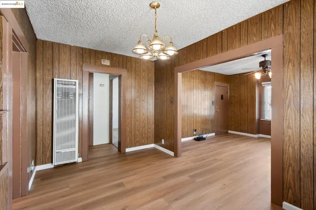 a view of an empty room with chandelier and glass door