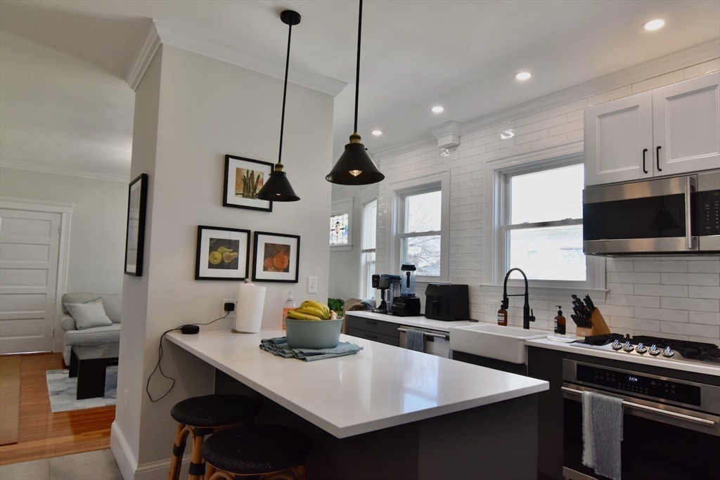 14 Castlerock Street, Unit 14 Boston, MA 02125 - Photo 12 of 32 a kitchen with stainless steel appliances a sink a stove a kitchen island a table and chairs