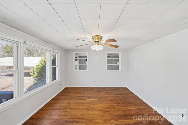 a view of empty room with wooden floor and fan