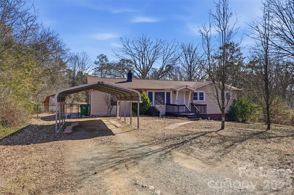 a view of house with a yard and large trees
