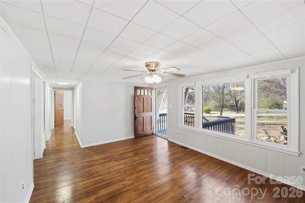 a view of an empty room with a window and wooden floor
