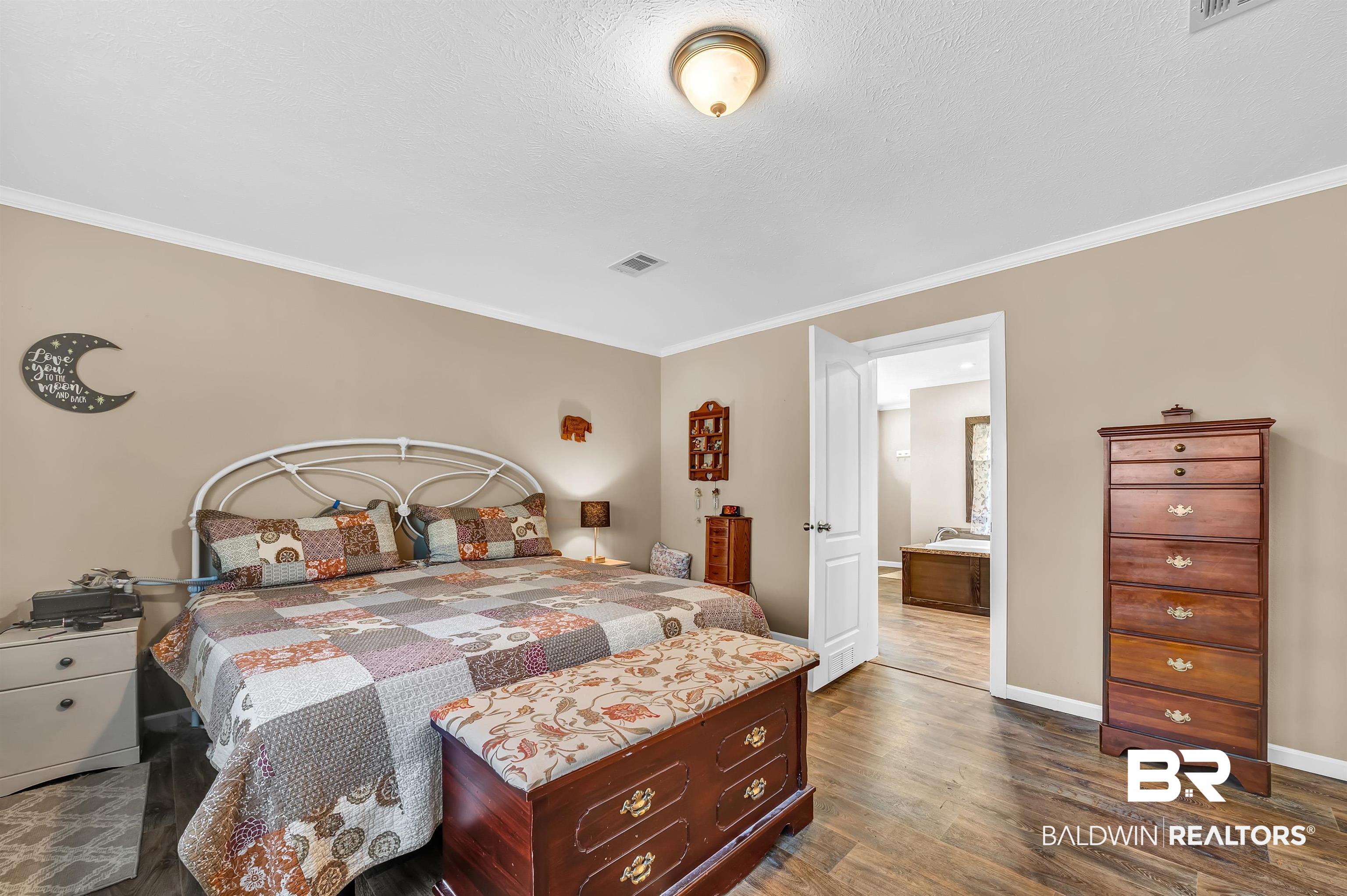 23233 Forland Road Silverhill, AL 36576 - Photo 19 of 33 Bedroom featuring baseboards, dark wood-style flooring, and crown molding