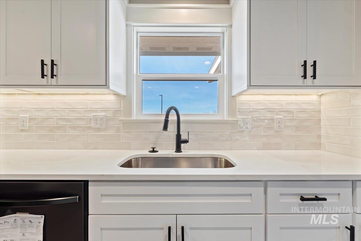 2435 North Black Cat Road Meridian, ID 83646 - Photo 11 of 32 Kitchen featuring white cabinets, dishwasher, light stone counters, and decorative backsplash