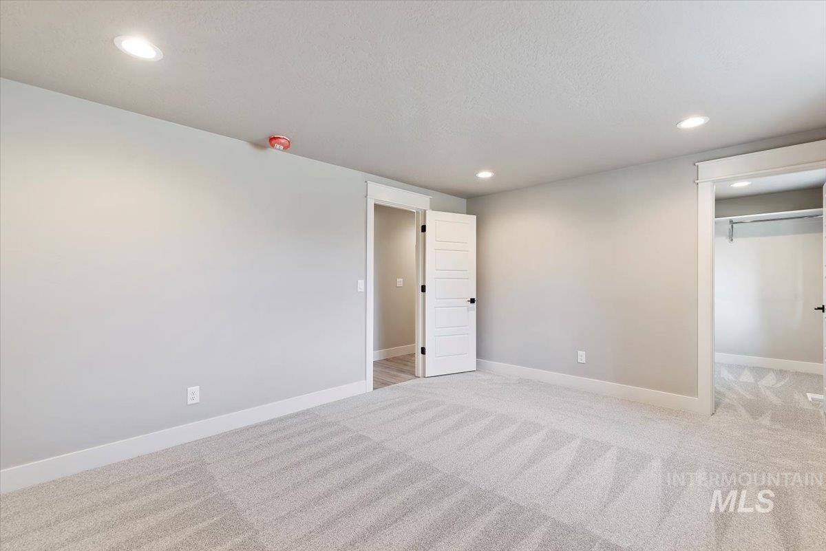 2435 North Black Cat Road Meridian, ID 83646 - Photo 20 of 32 Unfurnished bedroom featuring light colored carpet, recessed lighting, a spacious closet, and a textured ceiling