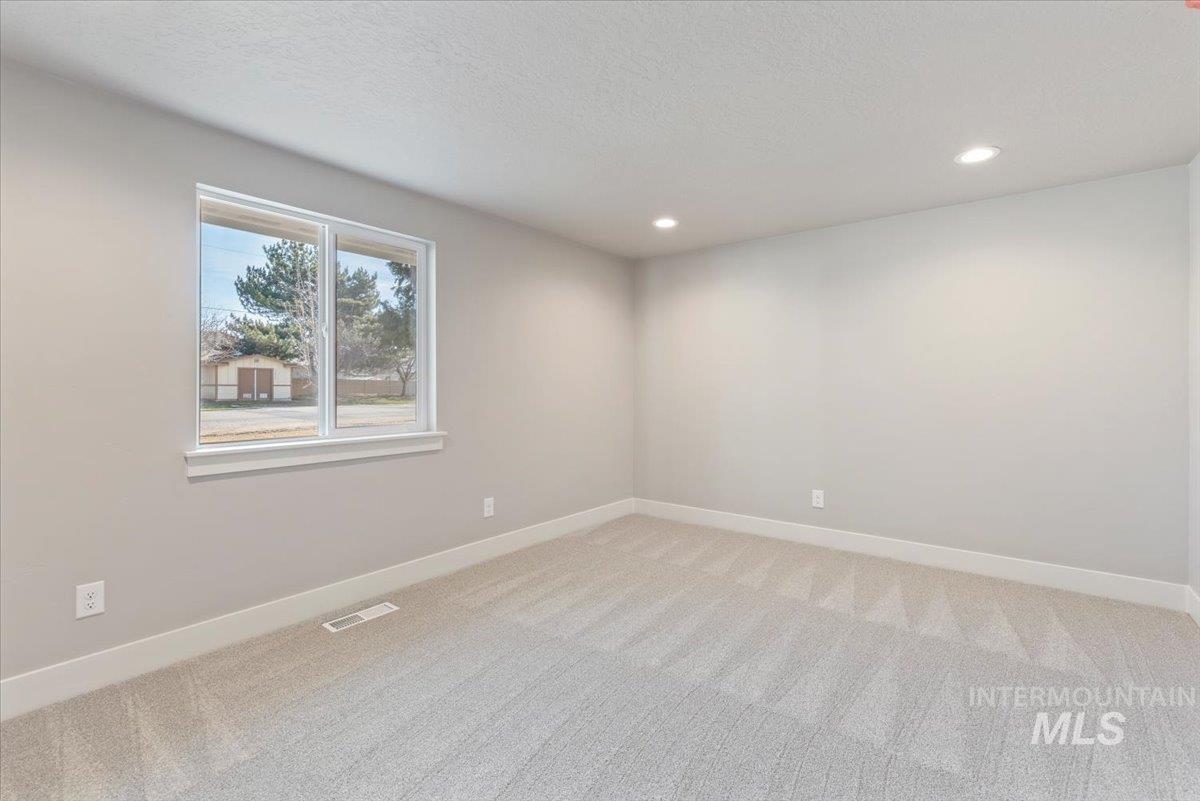 2435 North Black Cat Road Meridian, ID 83646 - Photo 22 of 32 Empty room with light colored carpet, recessed lighting, and a textured ceiling