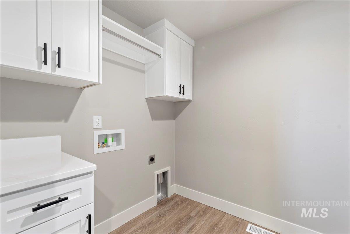 2435 North Black Cat Road Meridian, ID 83646 - Photo 27 of 32 Laundry room with electric dryer hookup, light wood-style floors, hookup for a washing machine, and cabinet space