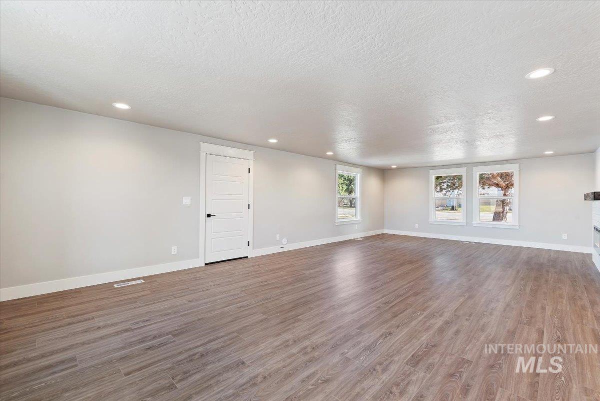 2435 North Black Cat Road Meridian, ID 83646 - Photo 5 of 32 Spare room featuring wood finished floors, a textured ceiling, and recessed lighting